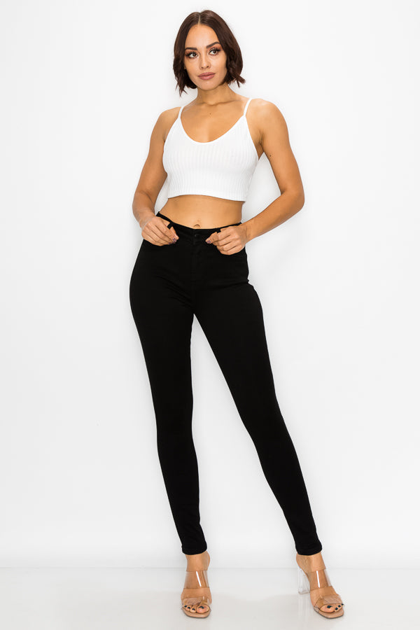 Woman wearing a white sports bra and black jeans on a white background