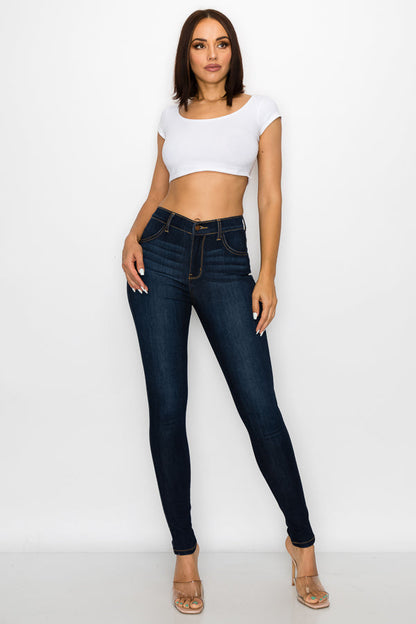 Woman wearing dark blue jeans and a white crop top on a white background